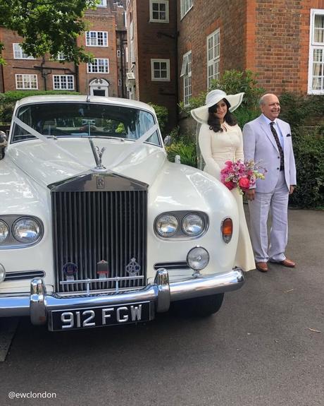 wedding car hire london premium retro car white brides standing bride in a hat and with a bright bouquet ewclondon