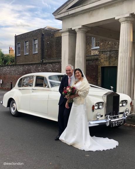wedding car hire london brides standing happily on the wheel of their white premium retro car against the background of ancient building ewclondon