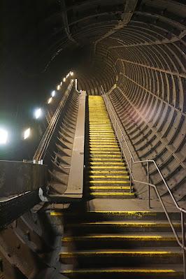 Hidden signs of Green Park station A circular passageway lined with iron panels leads upwards, and contains a long flight of stairs with the steps edged in yellow.