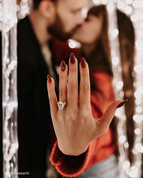 wedding ring finger blurre couple kissing shows engagement ring brilliantearth