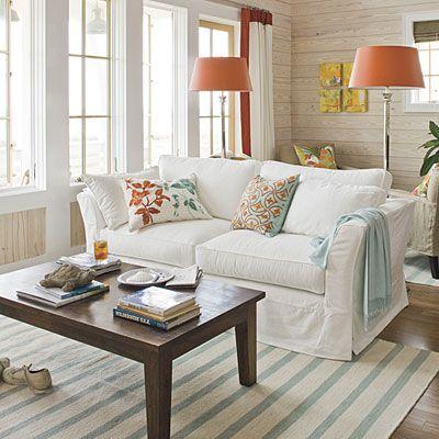 Choose a Sunny Palette    Crisp whites combined with punches of bright colors immediately transport you to the coast. In this living room, aqua accents in the pillows, throw, and rug mimic the ocean’s dazzling blues, and the pops of bright orange are inspired by the magnificent hues of the setting sun. Whitewashed horizontal shiplap planking evokes the feel of old Gulf-front beach houses.