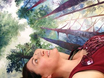 Artist Cedar Lee in her studio, beneath redwood forest painting Red Trunks. 48″ x 36″, Oil on Wood, © Cedar Lee 2014