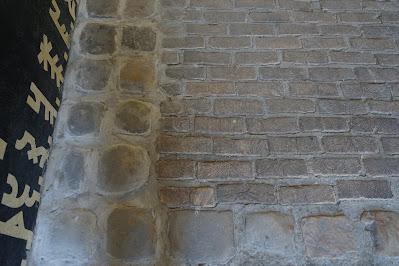 Photo showing close view of the wooden paving with stone paving to the left side of it.