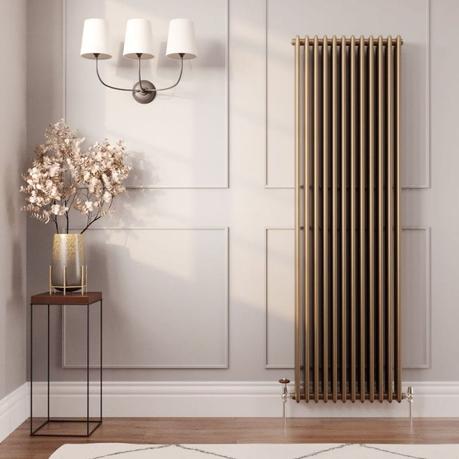 The 10 best column radiators for traditional and modern homes Milano Windsor metallic bronze vertical traditional column radiator on light wall nearby table with gold vase beneath triple light fitting