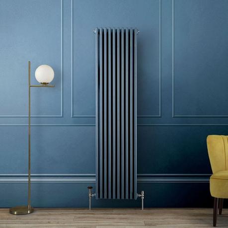A tall blue column radiator against a matching blue wall