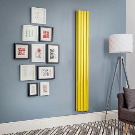 Why does my radiator keep turning off? Milano Aruba electric dandelion yellow vertical radiator on light blue wall nearby multiple framed art pictures and freestanding lamp