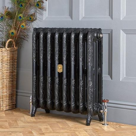 A guide to radiator repair and replacement costs Milano Beatrix black ornate cast iron radiator on light blue background nearby basket with peacock feathers