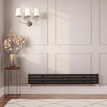 A guide to radiator repair and replacement costs Milano Aruba black horizontal designer radiator on cream wall nearby table with gold vase and artificial plant beneath triple lamp fitting