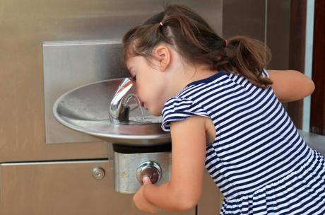 Young girl drinking from school fountain