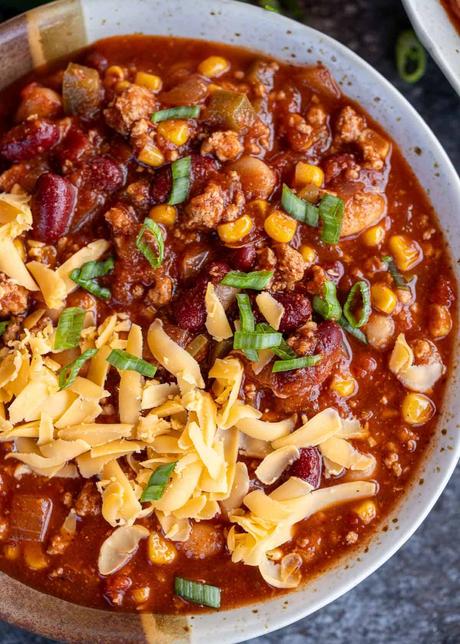 an overhead shot of turkey chili in a bowl with cheddar cheese