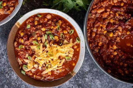 Chili Turkey Recipe an overhead shot of a pot of turkey chili and a bowl of turkey chili with shredded cheese