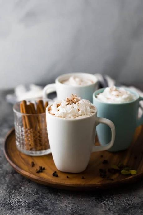 15+ Holiday Slow Cooker Recipes three cups of chai tea latte and a cup of cinnamon sticks on wood tray