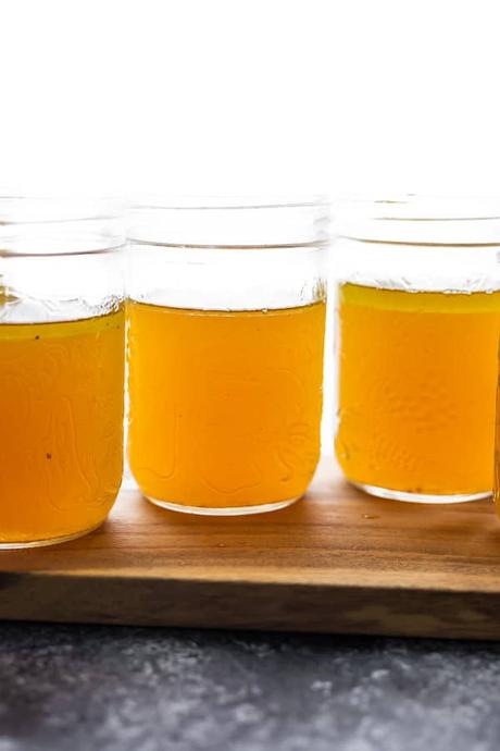 15+ Holiday Slow Cooker Recipes three mason jars filled with bone broth on a wood board