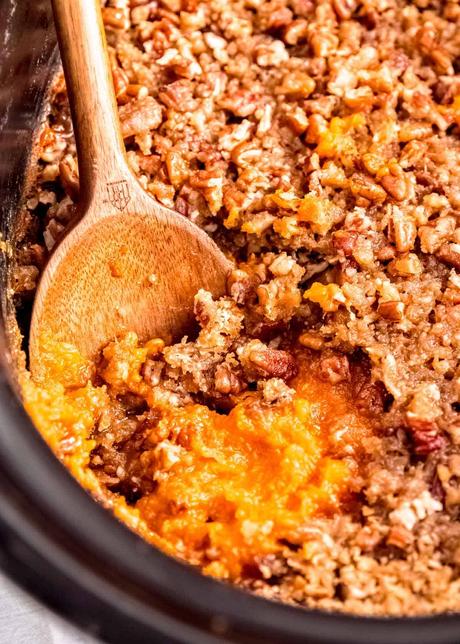 15+ Holiday Slow Cooker Recipes slow cooker sweet potato casserole in a black crockpot with a wooden spoon