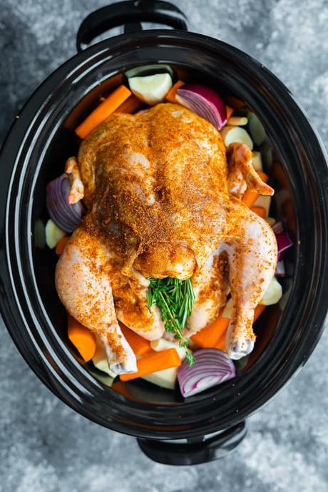 15+ Holiday Slow Cooker Recipes overhead shot of a whole chicken and veggies in a crockpot