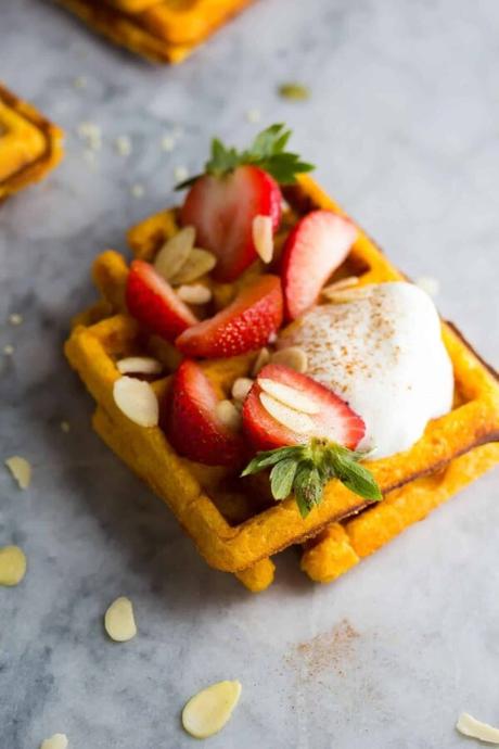 two sweet potato waffles with cream, almonds and strawberries