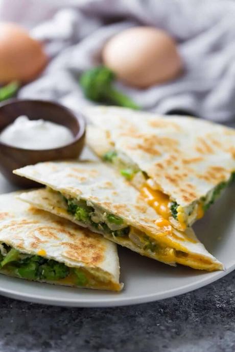 three triangle pieces of broccoli cheddar breakfast quesadilla on gray plate