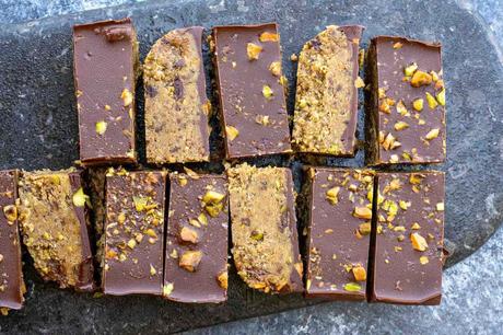 horizontal image showing tasty dark chocolate pistachio protein bars topped with crushed nuts