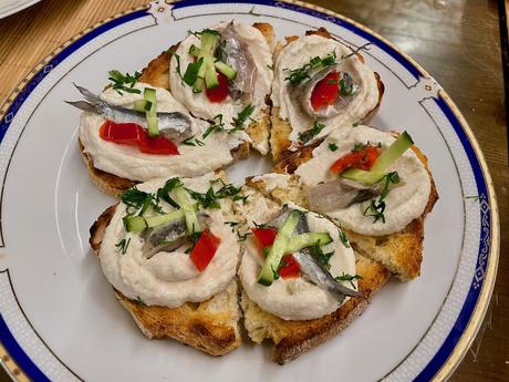 The Albanian Riviera: Best Beaches, Towns, and Hidden Gems Slices of toasted bread topped with creamy spread, anchovies, red pepper, and cucumber. A Mediterranean-inspired Albanian appetiser full of fresh and tangy flavours.