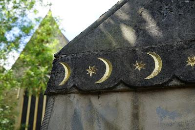 Photo showing detail of the mausoleum, decorated with gold crescent moons. In the background is a stone church.