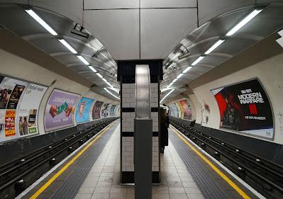 Mysterious metalwork quiz: answers Photo: at the center is a free-standing Tube roundel, side-edge towards the camera. It is on an island platform with poster-lined walls and tracks to either side.
