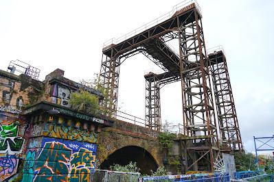 Mysterious metalwork quiz: answers A brick wall and archway. Above it rise four open metalwork pillars, joined by a H-shaped metal top.