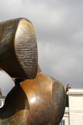 Mysterious metalwork quiz: answers Section of an abstract, bronze-coloured metal sculpture. In the background are glimpses of cream-painted London townhouses.