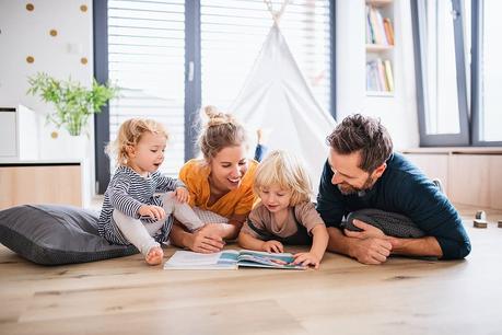 Parents and children reading together in a cozy living room, promoting family bonding and healthy indoor air quality.