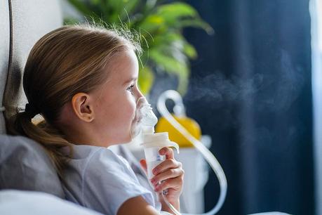 Child using an inhaler for asthma relief in a cozy home setting.