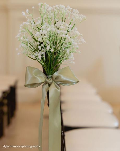 An Emerald & Sage, Zero-Alcohol Real Wedding wedding chair decorated with baby’s breath and green ribbon dylanhancockphotography
