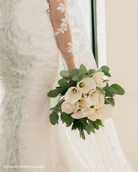 An Emerald & Sage, Zero-Alcohol Real Wedding a bride holds her bouquet in a close up shot that highlights the elegance of her wedding attire and floral arrangement dylanhancockphotography