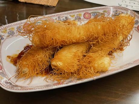 Plate of crispy fried kataif cheese rolls drizzled with honey or syrup. A popular Albanian appetiser that combines crunch and sweetness.