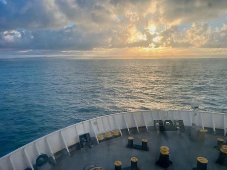 Serene ocean view sailing into the sunrise from the front deck of the ferry from Bari, Italy to Durres, Albania with calm waters and dramatic cloudscape.