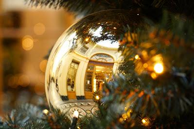 Photo of a gold bauble in a Christmas tree, reflecting part of a 19th century shopping arcade.