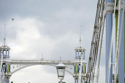 Photo showing detail of the bridge, with white cables and blue and green details on their supporting pillars.