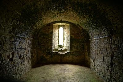 Weathered and worn: Battle Abbey's stones Photo of an arched stone room with curved ceiling and earth floor.