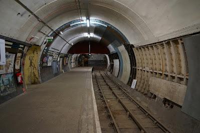 Aldwych Station posters: truth or lie? Photo of an empty Tube platform, with the track to the right. The wallls have different coverings, with posters visible towards the further end.