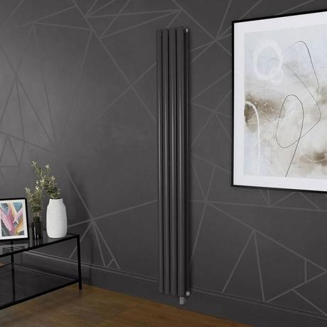 Milano x ECOSO Aruba electric carbon gray vertical designer radiator on dark wall nearby large framed artwork and small table with vases and picture frame