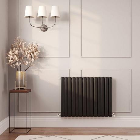 Milano Aruba black horizontal designer radiator on cream wall nearby small table with vase and fake houseplant beneath triple light fitting