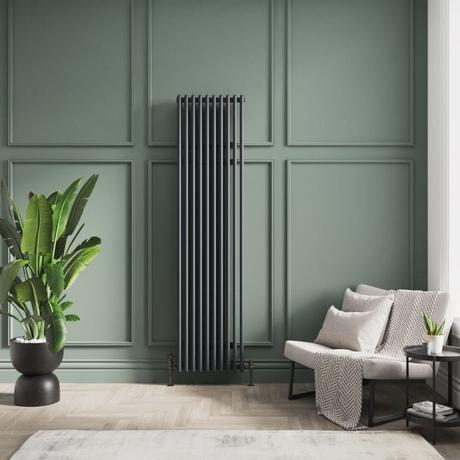 8 radiator ideas for period properties Milano Esme black vertical aluminum traditional radiator on green wall nearby white chair and houseplant in black vase