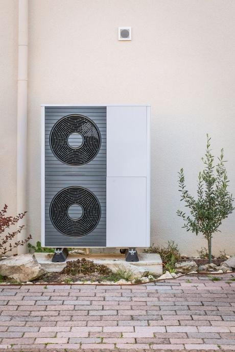 Two white and gray air source heat pumps installed outside a home