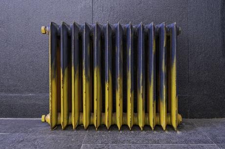 Retro blue and yellow radiator with worn-out effect on gray flooring and background