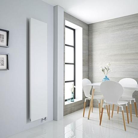 Milano x ECOSO Riso white electric flat panel vertical designer radiator on white wall nearby white table and chairs and vertical window inset from modern gray wall
