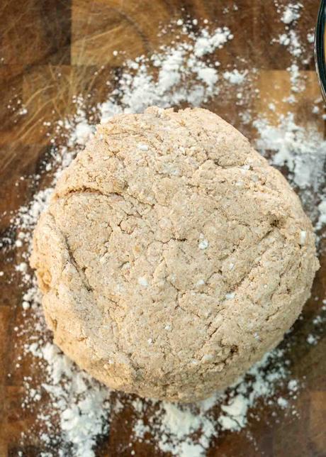 bagel dough being patted out on wooden cutting board