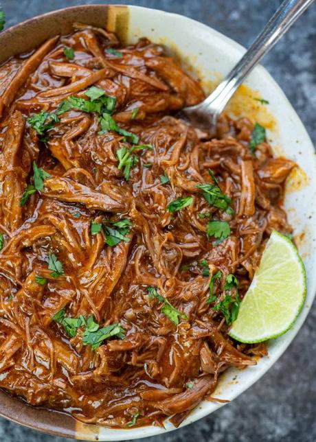 Shredded Beef Tacos a bowl full of juicy shredded beef topped with fresh herbs with a side of lime wedge