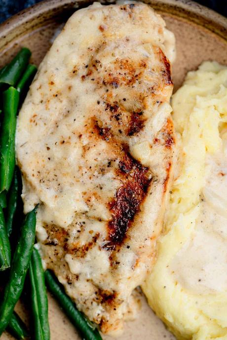 overhead shot of creamy garlic chicken on a plate with potatoes and green beans