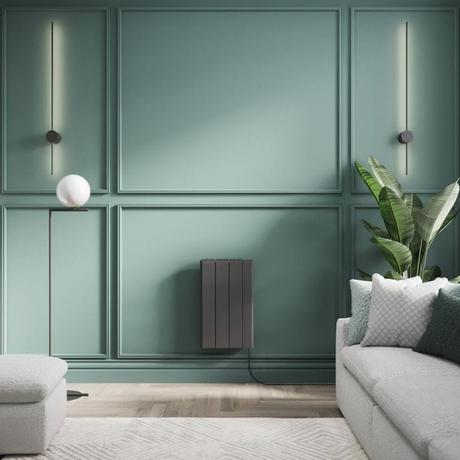 ECOSO Tuc graphite ceramic core smart electric heater on green wall nearby houseplant by light gray settee