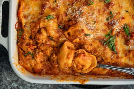 a spoon scooping up cheesy baked tortellini