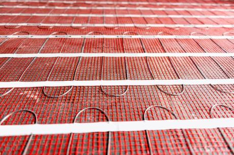 Electric underfloor heating mats on concrete floor in the form of radiant heating cable attached to fiberglass mesh