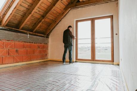 Man stood on top of fresh underfloor heating installation in new-build construction site house